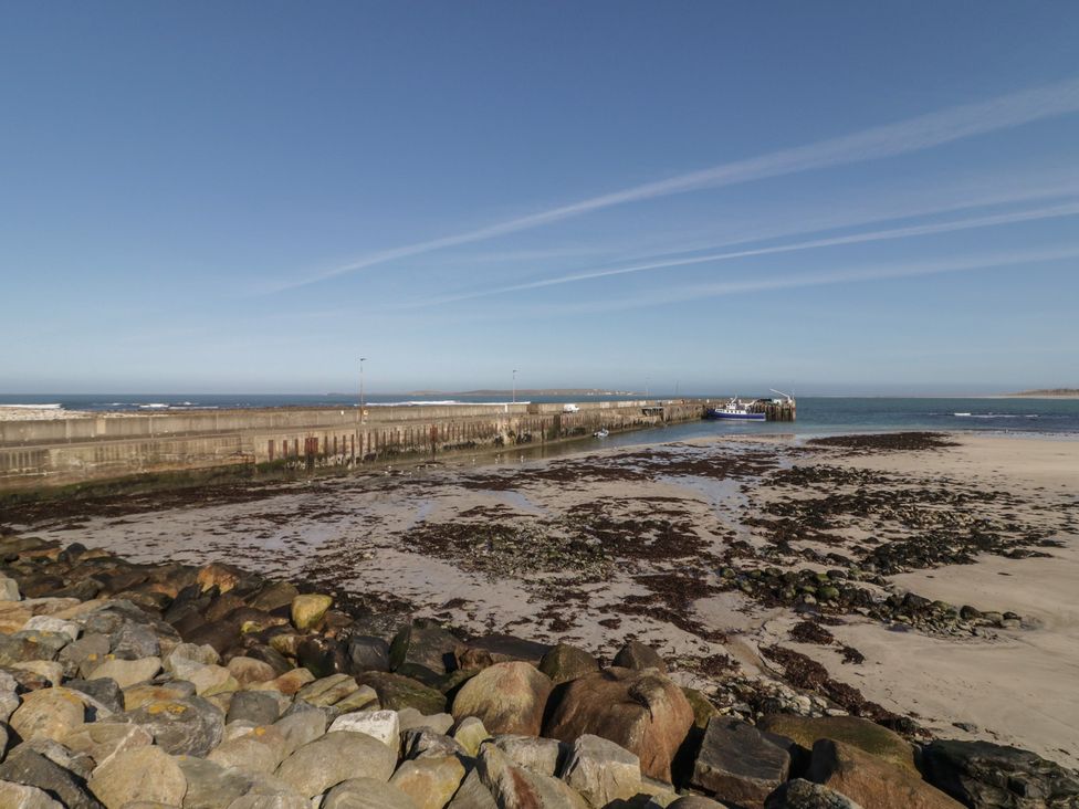 A pier extending into the ocean with rocks and sand at Cabin 7 Toraigh Gortahawk