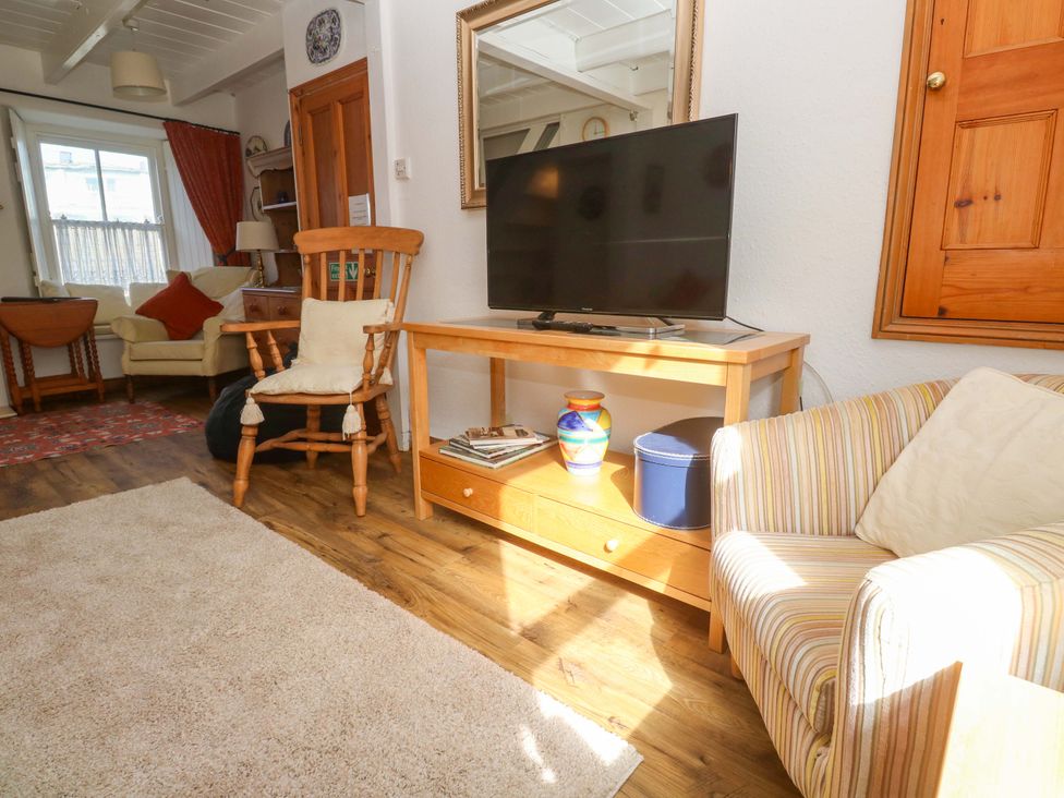 A living room with a TV on a table at St. Dominic Cottage in St. Ives