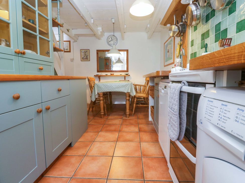A kitchen with cabinets and a table at St. Dominic Cottage in St. Ives