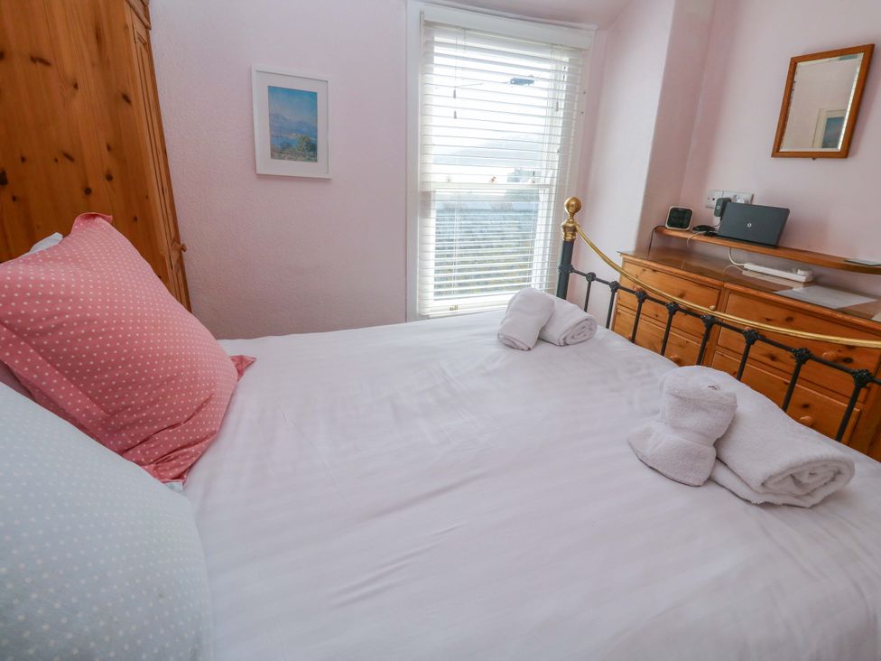 A bedroom with a bed and wooden dresser at St. Dominic Cottage in St. Ives