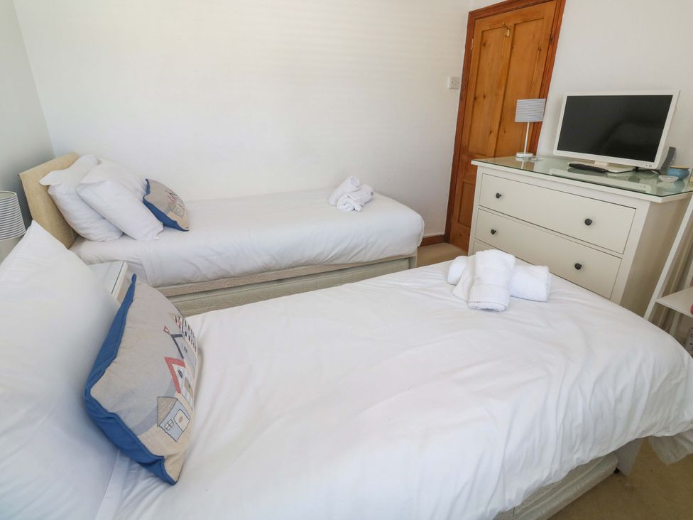A bedroom with twin beds and dresser at St. Dominic Cottage in St. Ives