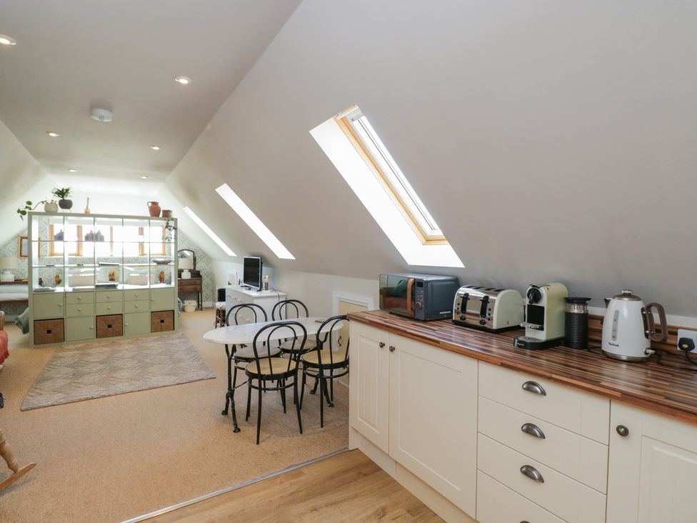 A kitchen with appliances and dining area at The Hideaway Loft in Chippenham