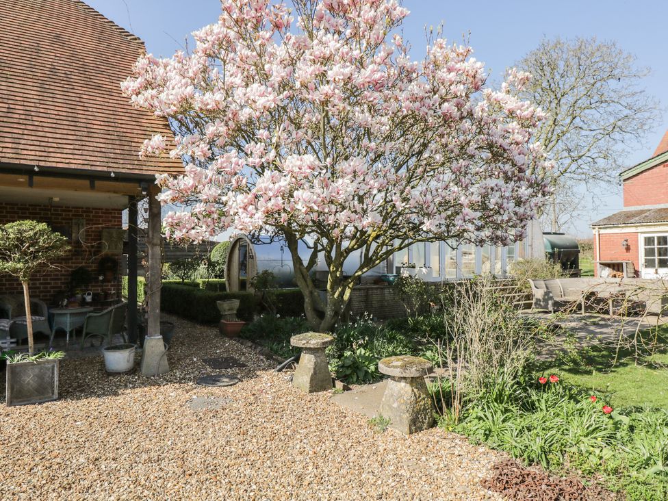 A garden with a flowering tree and seating area at The Hideaway Loft in Chippenham
