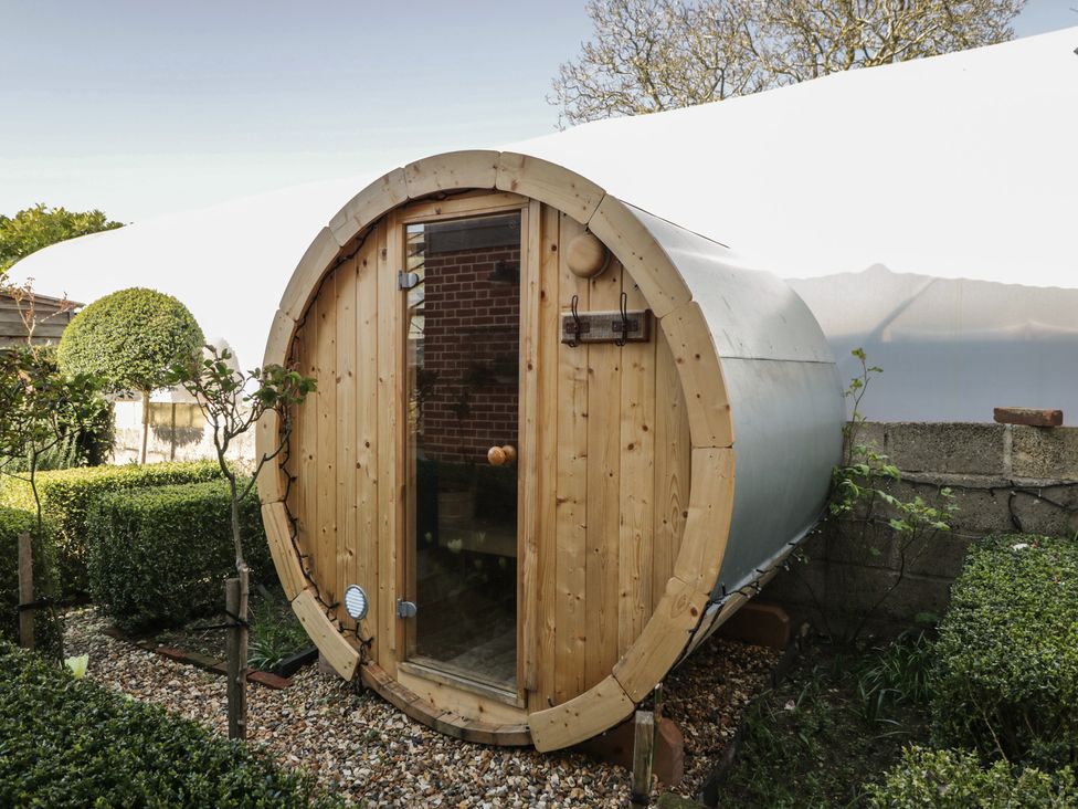 A wooden barrel-shaped structure in a garden at The Hideaway Loft in Chippenham