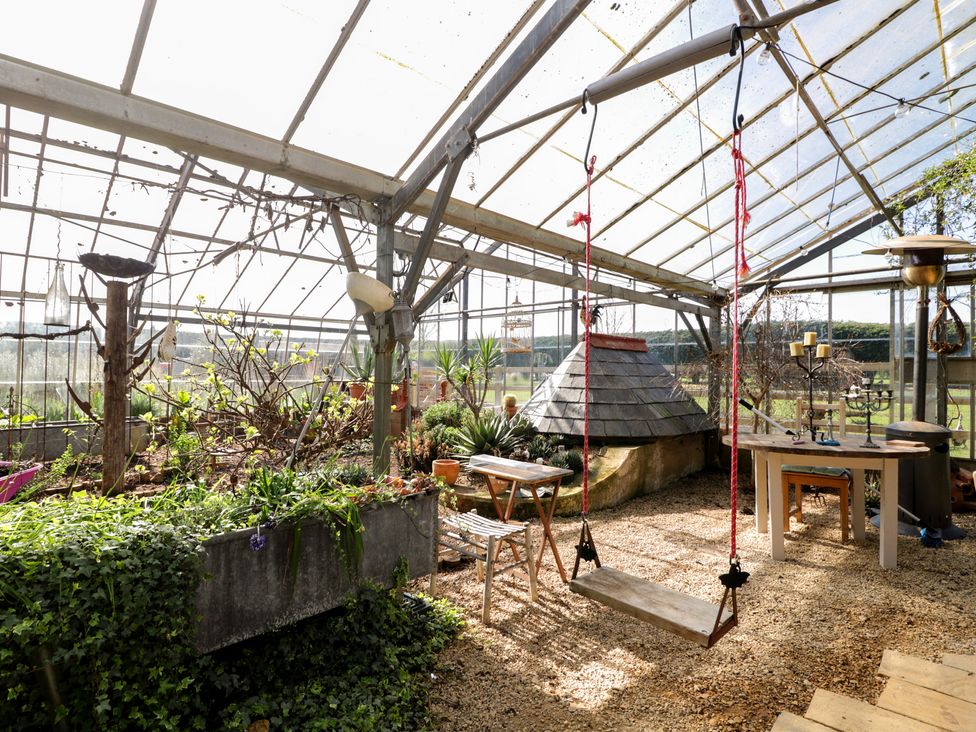 A garden with a swing, table, and plants in The Hideaway Loft in Chippenham