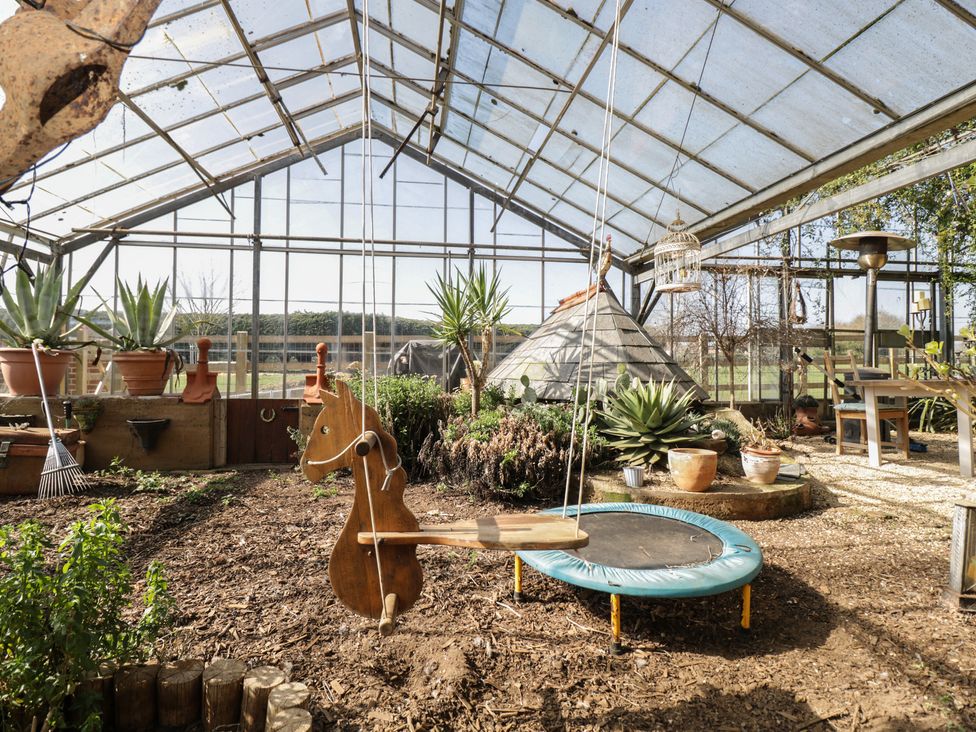 A greenhouse with a trampoline, swing and plants at The Hideaway Loft in Chippenham