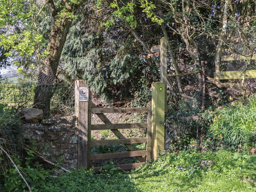 A gate with a sign and trees at Upper Frogpool Cottage in Crediton