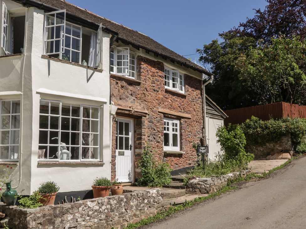 An exterior view of a stone cottage with windows and a door at Upper Frogpool Cottage Crediton