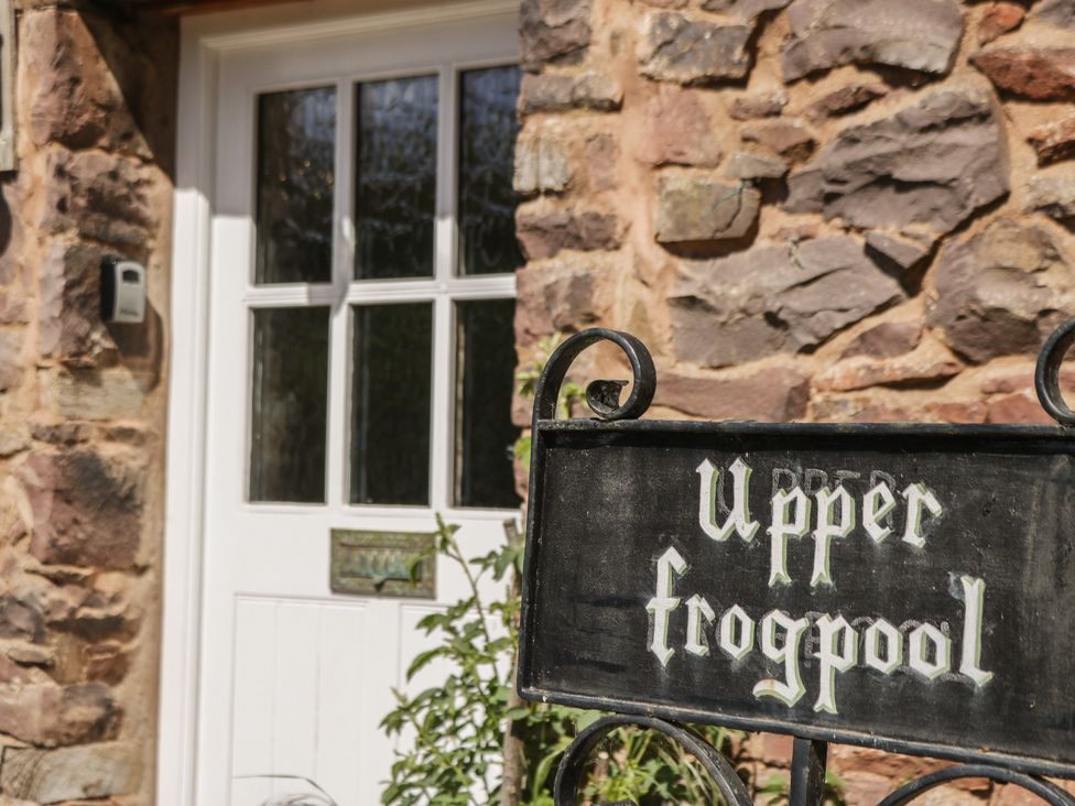 An entrance with a stone wall and door at Upper Frogpool Cottage in Crediton