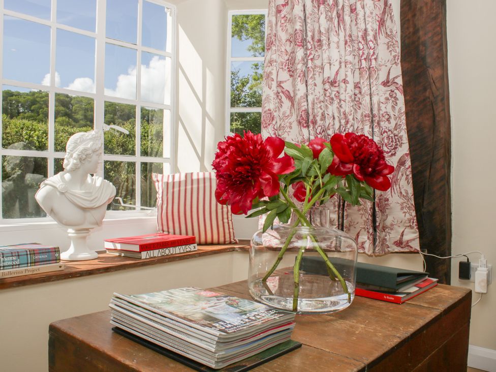 A living room featuring a vase with flowers and books at Upper Frogpool Cottage in Crediton