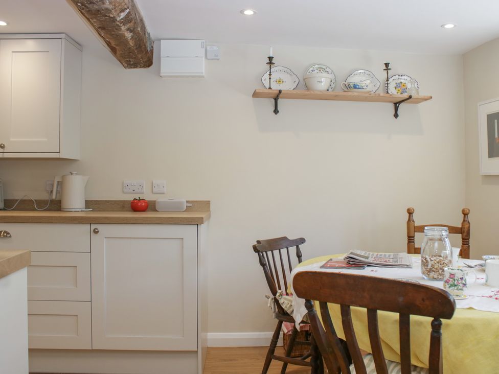 A kitchen with cabinets and a table at Upper Frogpool Cottage in Crediton