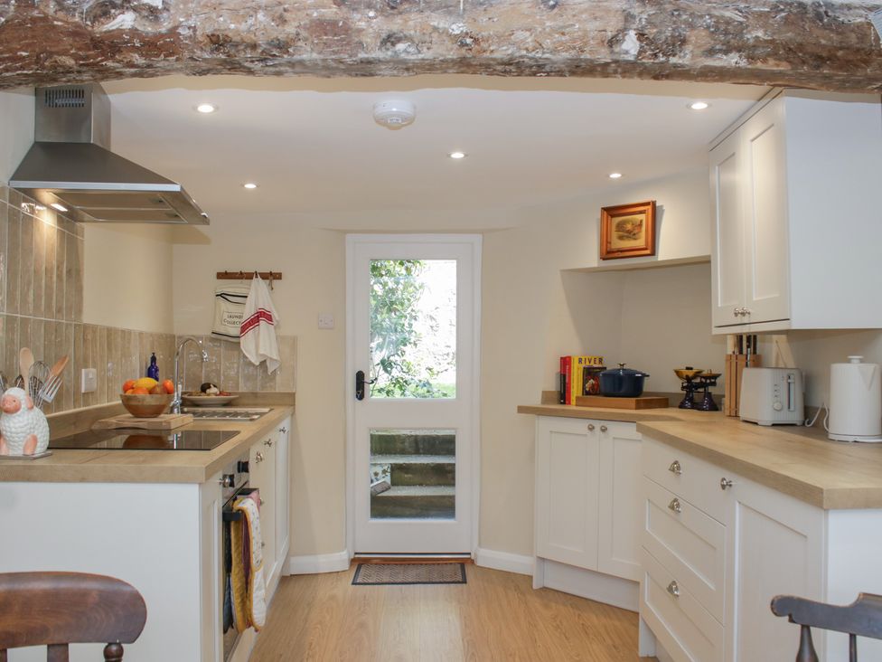 A kitchen with a sink, stove, and bowl of fruit at Upper Frogpool Cottage in Crediton