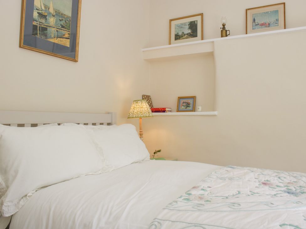 A bedroom with a bed and shelf displaying pictures at Upper Frogpool Cottage in Crediton