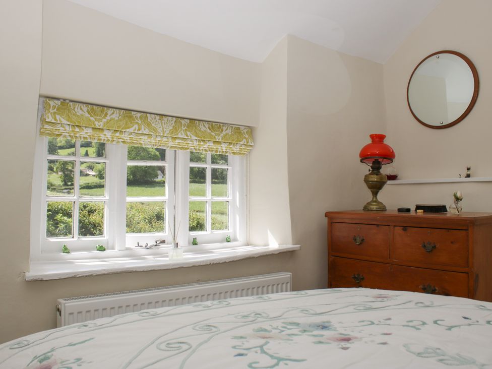 A bedroom with a window and a dresser at Upper Frogpool Cottage in Crediton