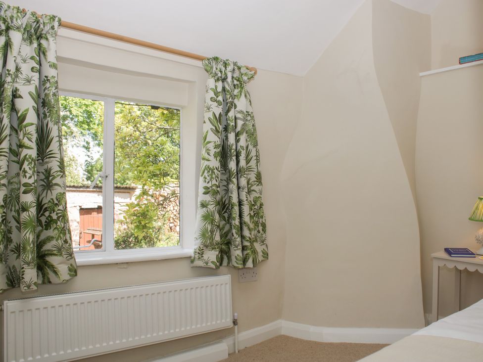 A bedroom with a window and curtains at Upper Frogpool Cottage in Crediton