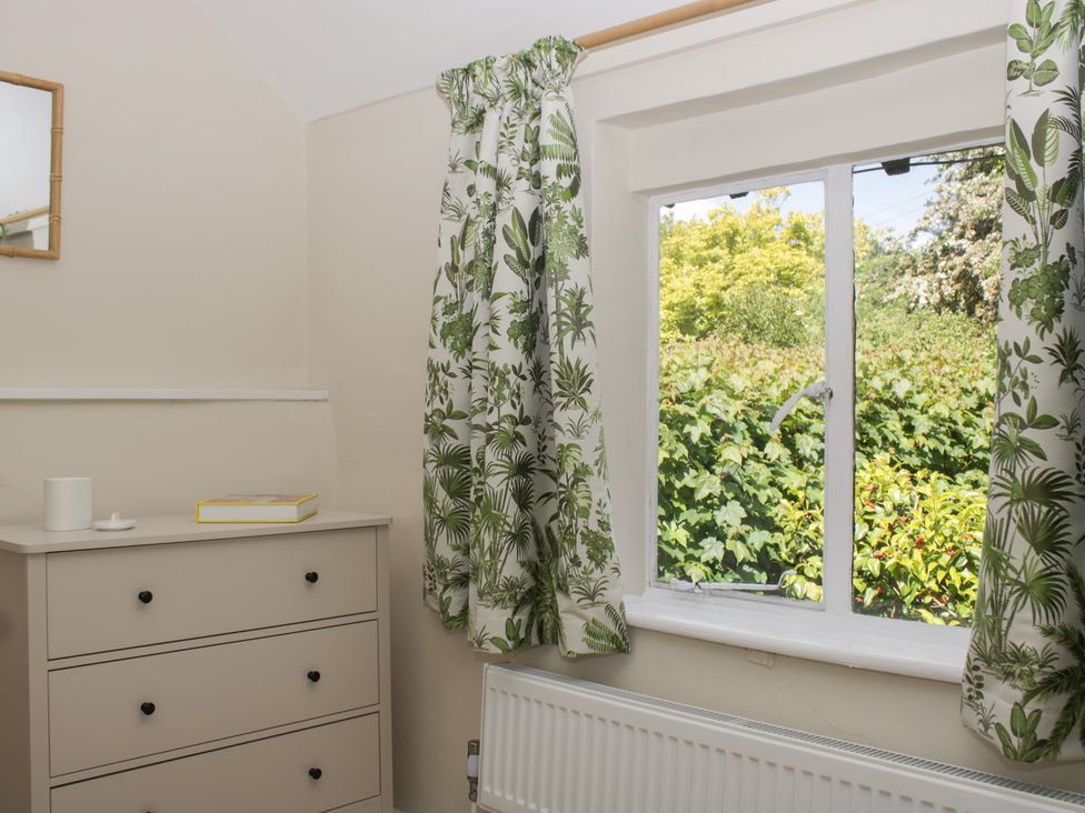 A bedroom with a dresser and window at Upper Frogpool Cottage in Crediton