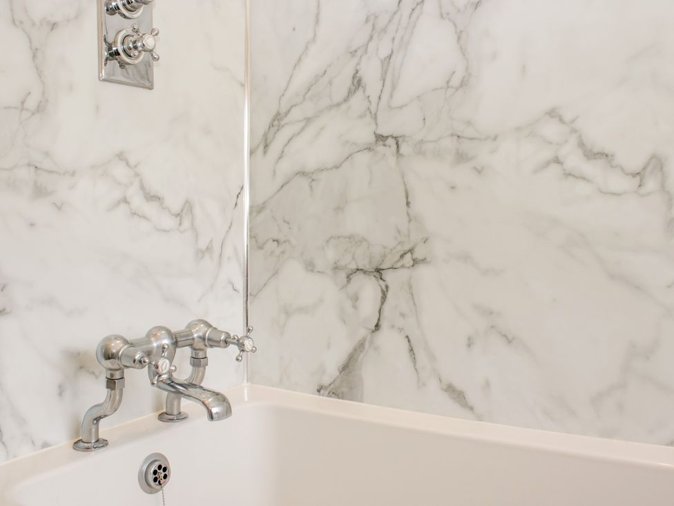 A bathtub with chrome taps in a bathroom at Upper Frogpool Cottage in Crediton