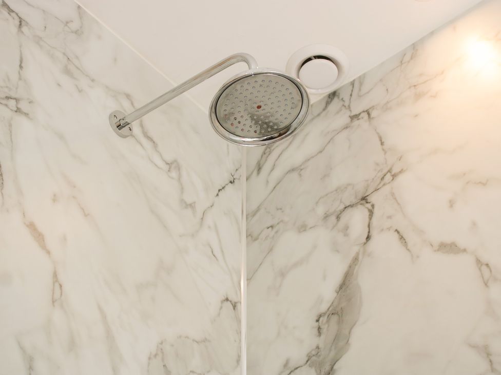 A shower head mounted on a marble wall at Upper Frogpool Cottage in Crediton