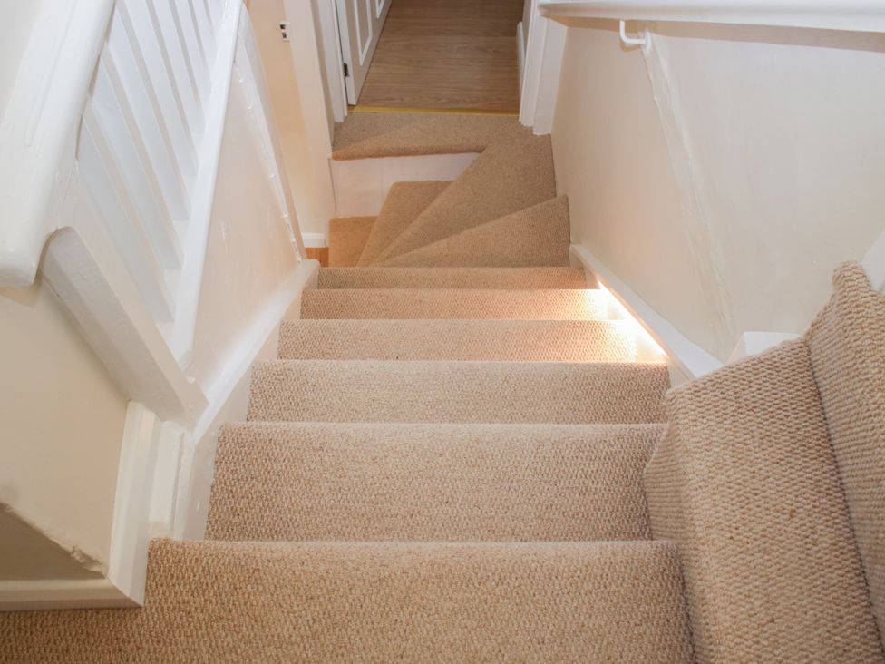 A staircase with carpet leading to a doorway at Upper Frogpool Cottage in Crediton