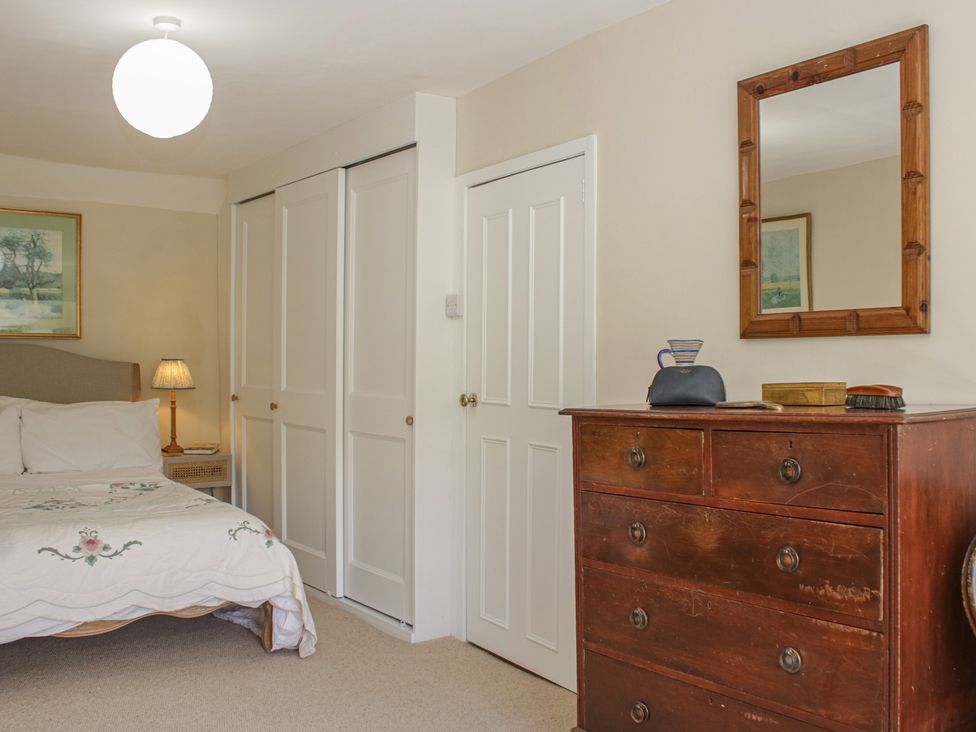 A bedroom with a bed and dresser at Upper Frogpool Cottage in Crediton