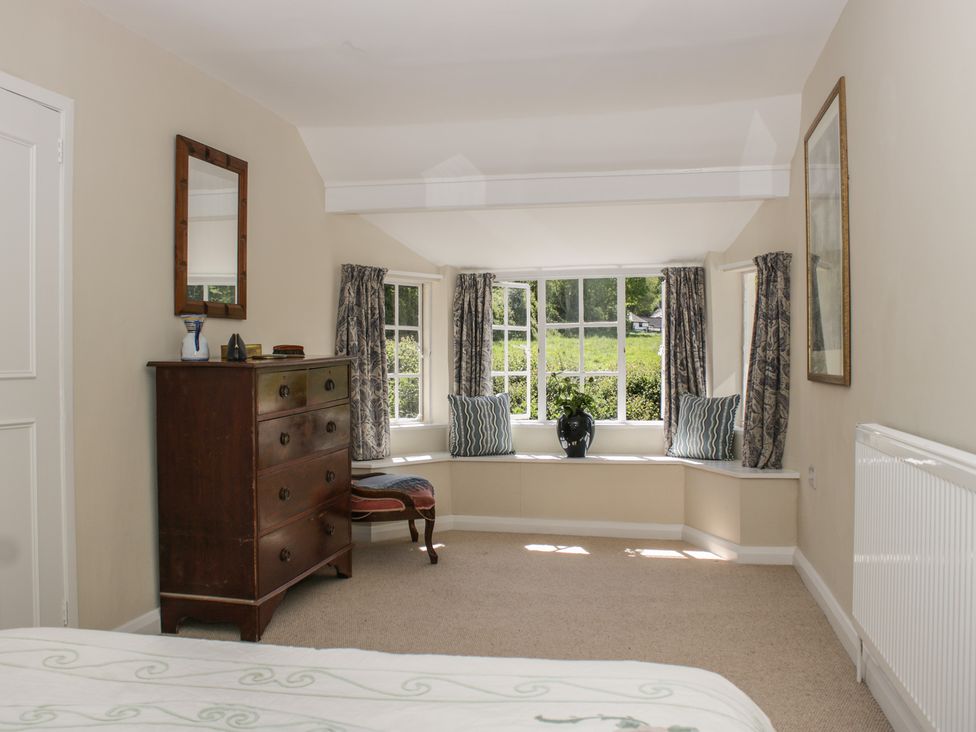 A bedroom with a dresser and window seat at Upper Frogpool Cottage in Crediton