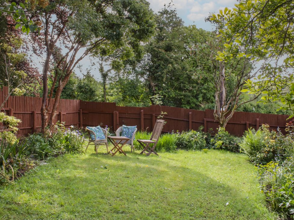 A garden with chairs and a table at Upper Frogpool Cottage in Crediton