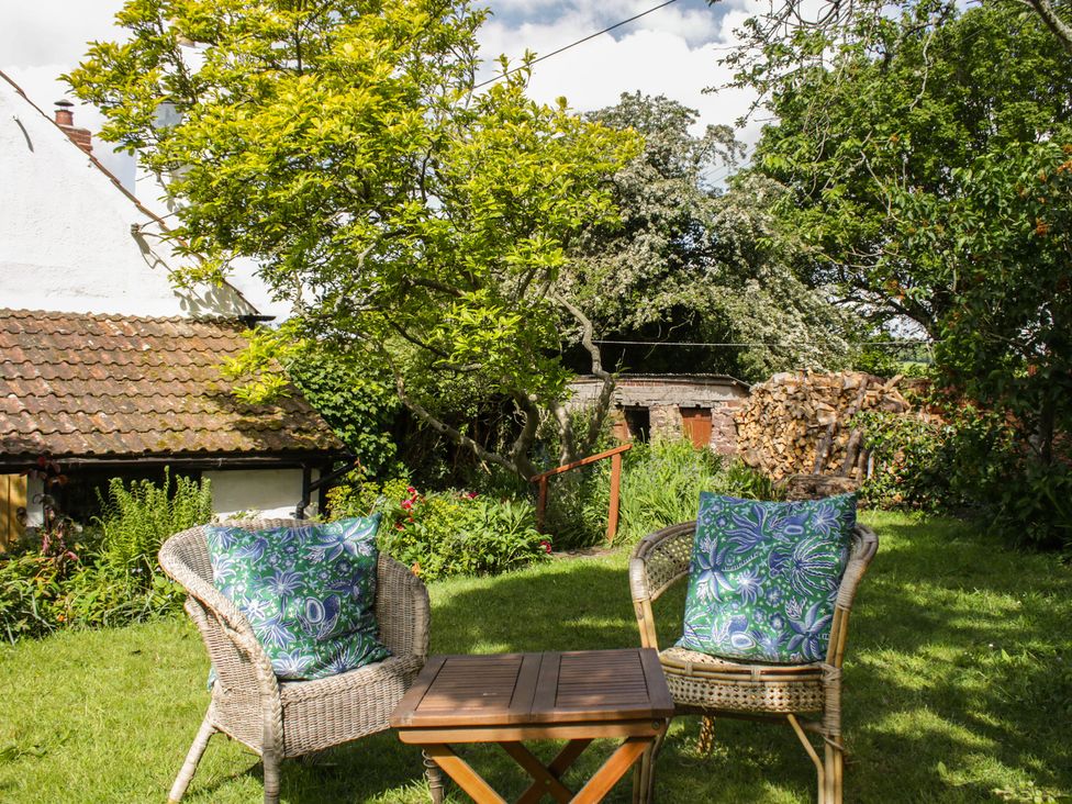 A garden with chairs and a table at Upper Frogpool Cottage in Crediton