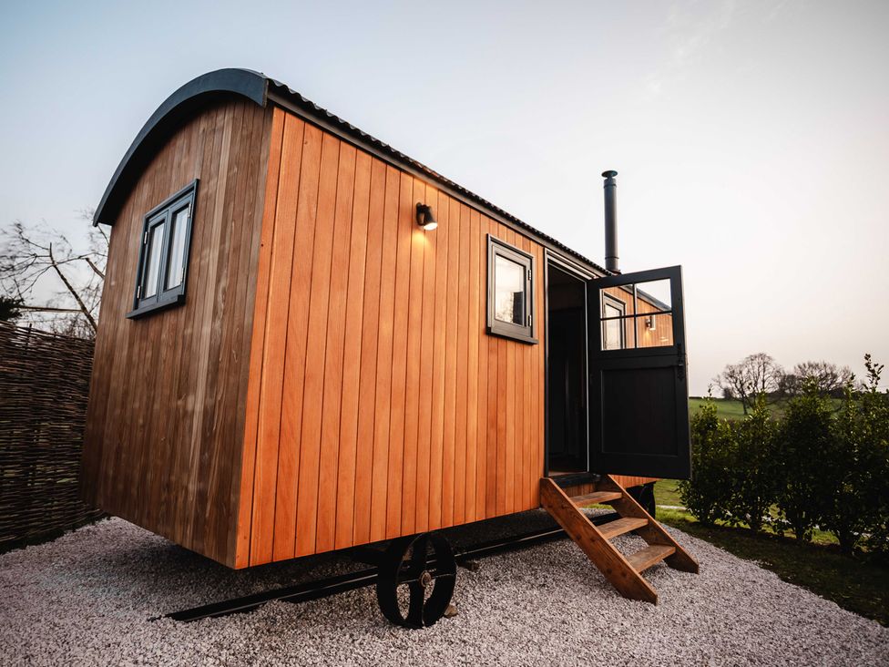 A wooden cabin with steps and an open door at Shepherds View in Bradley near Ashbourne