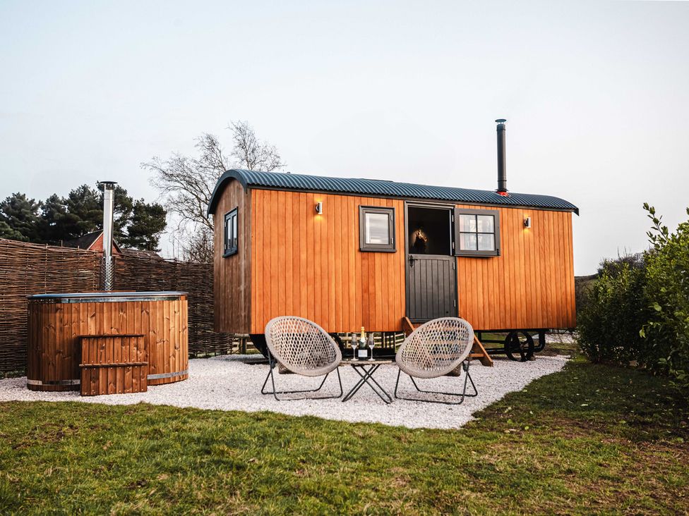 A wooden cabin with hot tub and chairs outside at Shepherds View in Bradley near Ashbourne