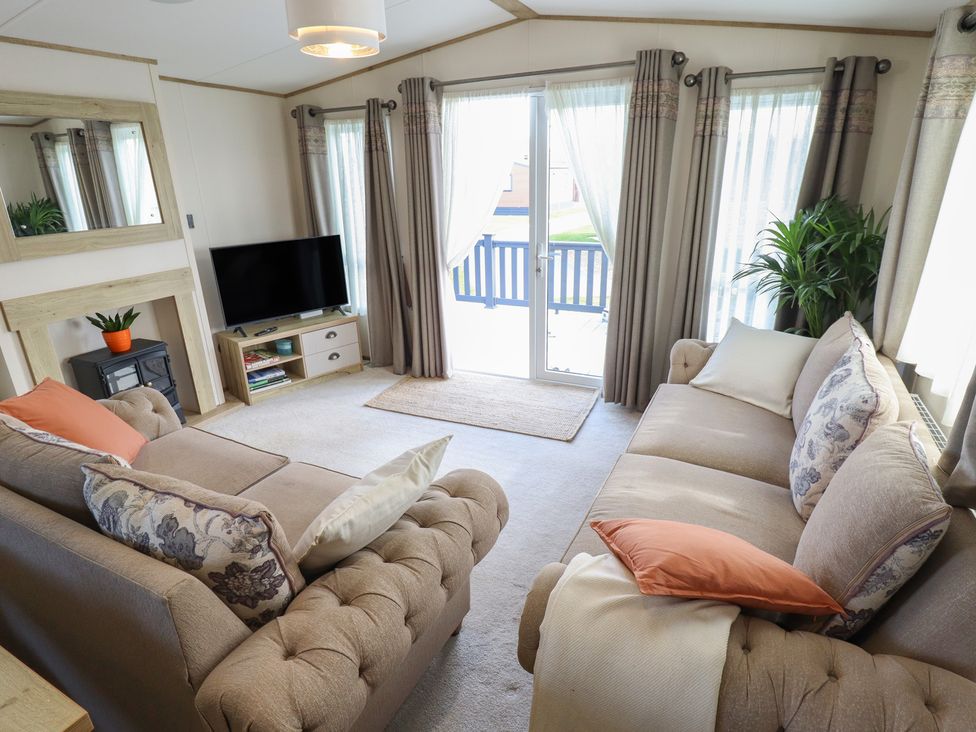 A living room with a sofa and television at Number 6 - Sandy Beach Holiday Park Bacton