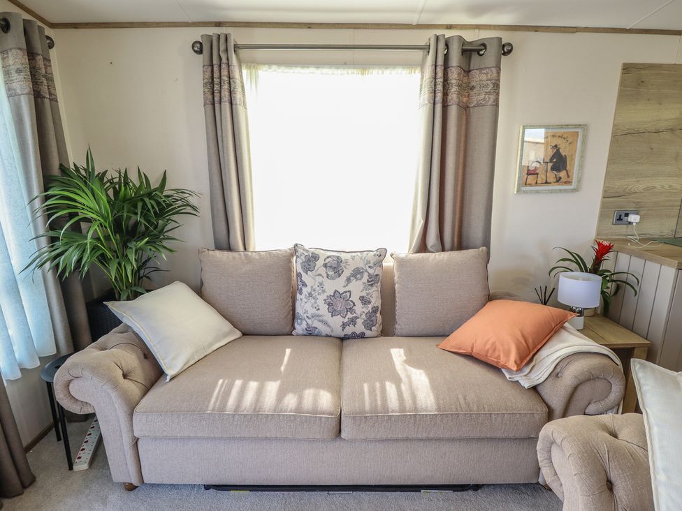 A living room with a sofa and cushion at Number 6 - Sandy Beach Holiday Park in Bacton