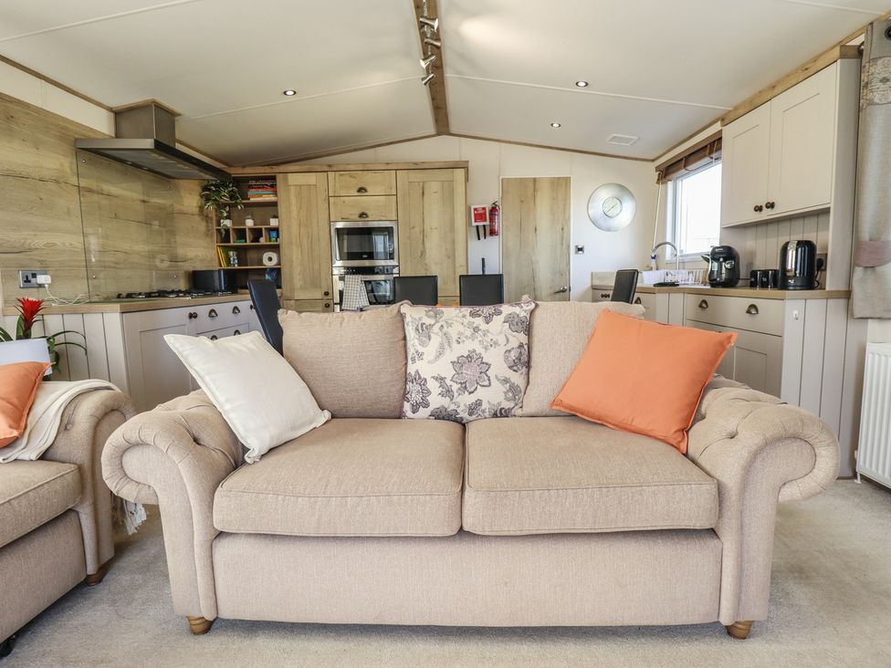 A living room with a sofa and kitchen in Number 6 - Sandy Beach Holiday Park Bacton