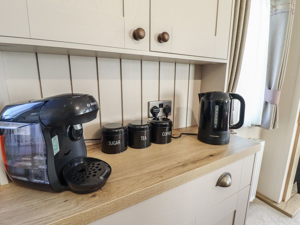 A kitchen countertop with coffee machine, kettle, and containers for sugar, tea, and coffee at Number 6 - Sandy Beach Holiday Park in Bacton