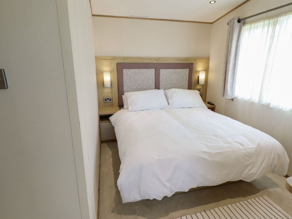 A bedroom with a bed and curtains at Number 6 - Sandy Beach Holiday Park in Bacton
