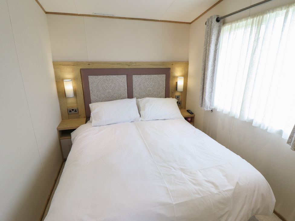 A bedroom with a double bed and curtains at Number 6 - Sandy Beach Holiday Park Bacton