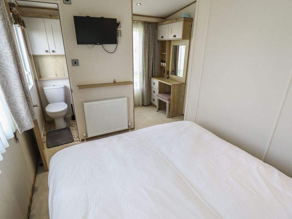 A bedroom with a bed and a television at Number 6 - Sandy Beach Holiday Park in Bacton