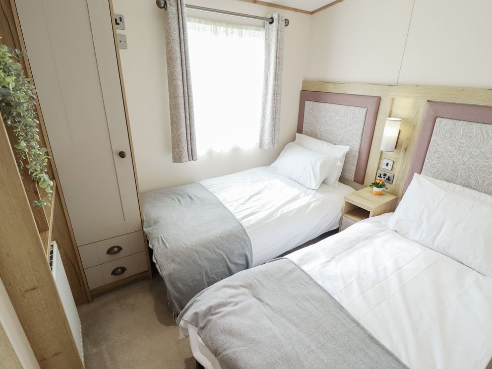 A bedroom with two single beds and a window at Number 6 - Sandy Beach Holiday Park in Bacton