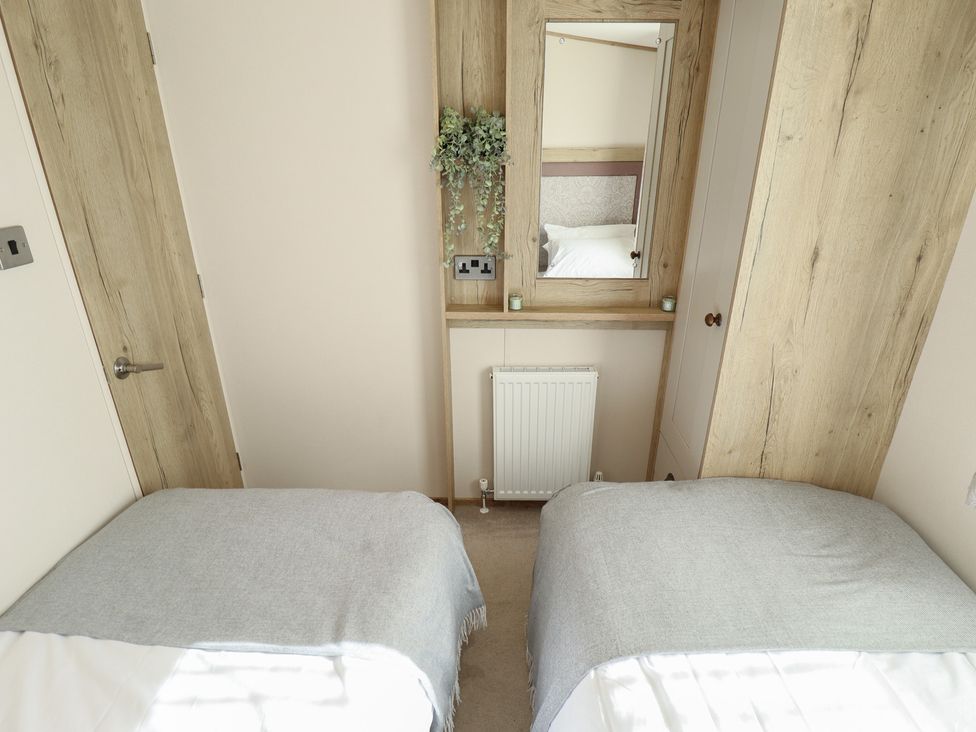 A bedroom with two beds and a mirror at Number 6 - Sandy Beach Holiday Park in Bacton