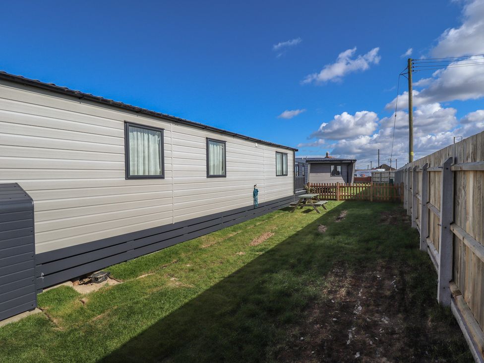 An outdoor view of a caravan and garden at Number 6 - Sandy Beach Holiday Park in Bacton