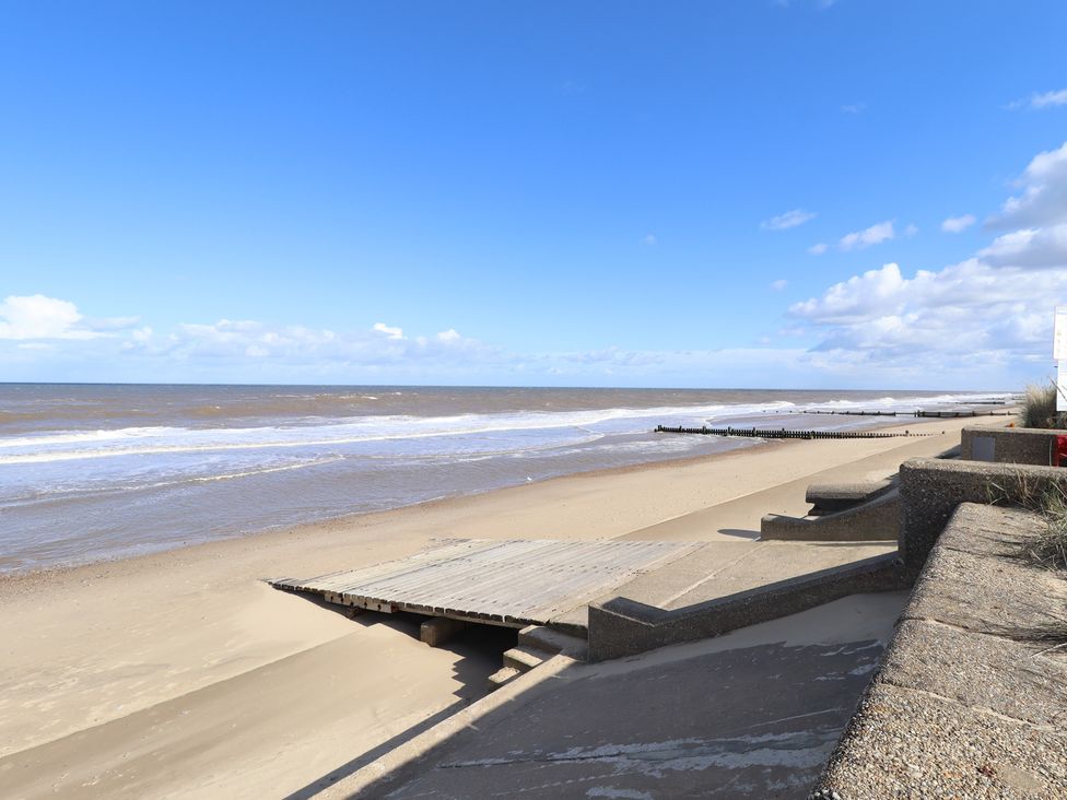 A beach scene with a boardwalk leading to the sea at Number 6 - Sandy Beach Holiday Park, Bacton