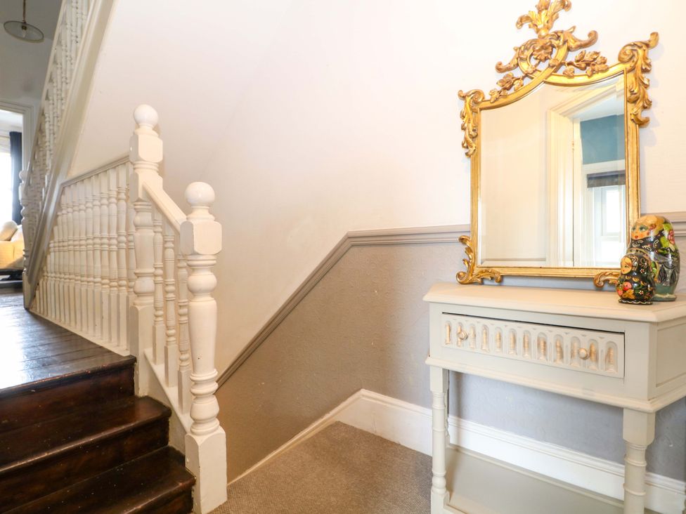 A hallway with a staircase and a console table with a mirror at Tickety-Boo in Broadstairs