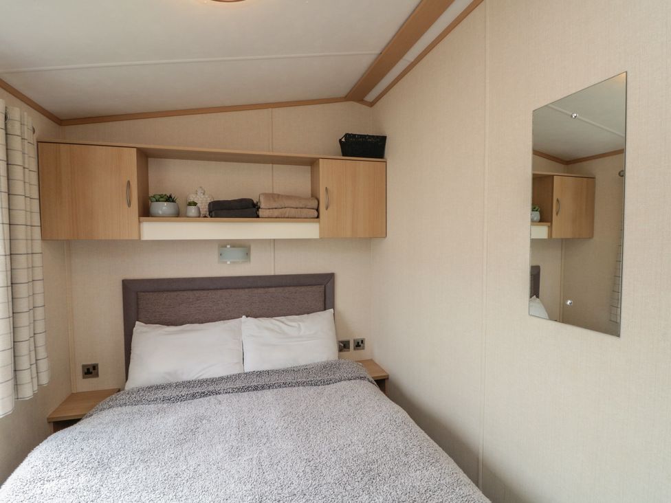 A bedroom with a bed and shelves at 21 Dunlin Dell in Flamborough