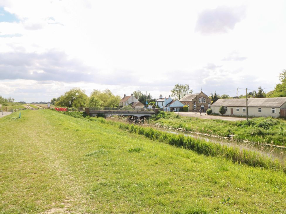 A view of a path alongside water with houses and trees at Hazel in 