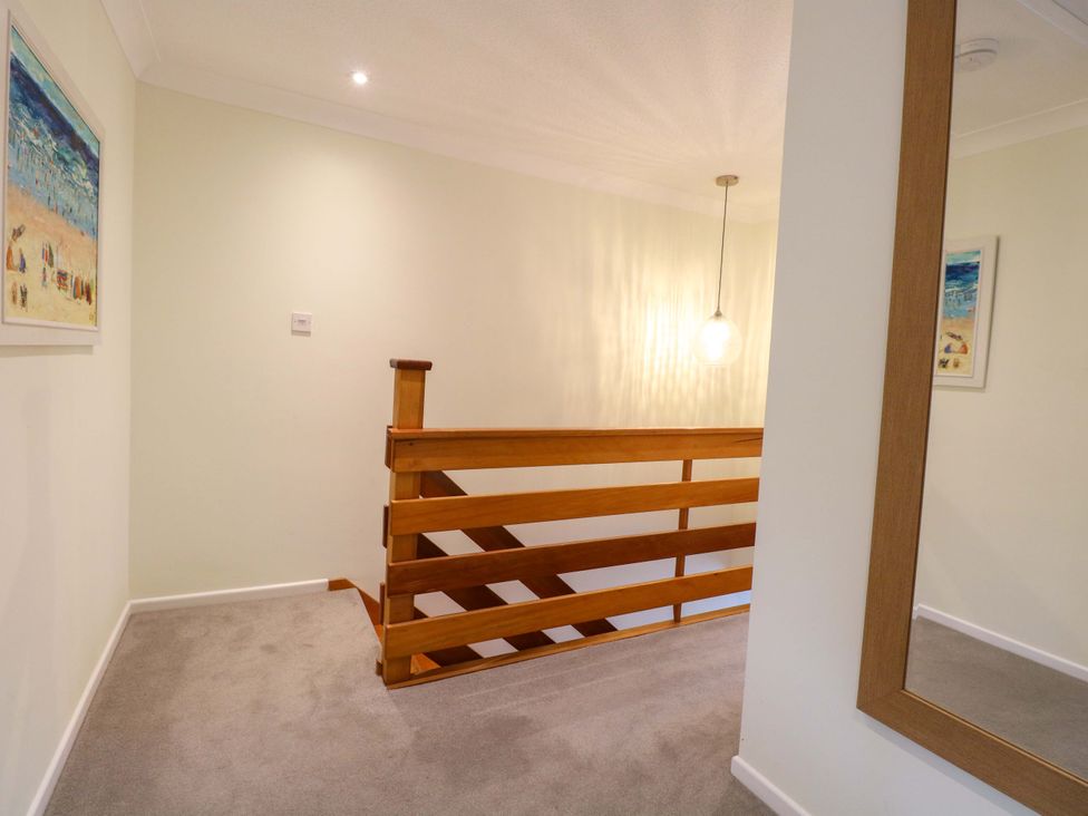 A hallway with a wooden stair railing and wall art at Old Summer in Northrepps near Cromer