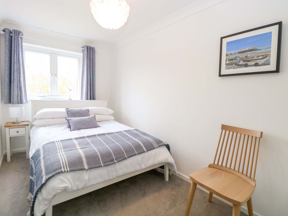 A bedroom with a bed, side table, lamp, and window at Old Summer near Cromer
