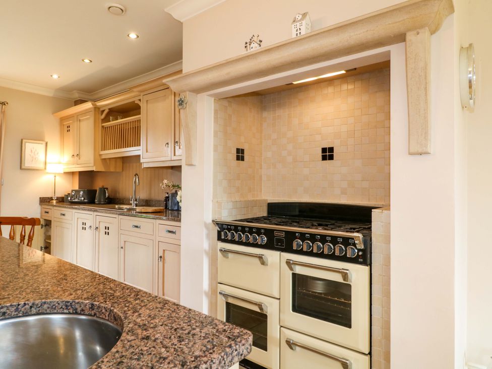A kitchen with a stove, sink and kitchen cabinets at The Garden House in Alton
