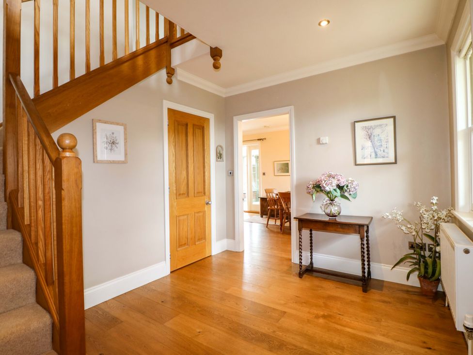A hallway with a staircase and a table with flowers at The Garden House in Alton