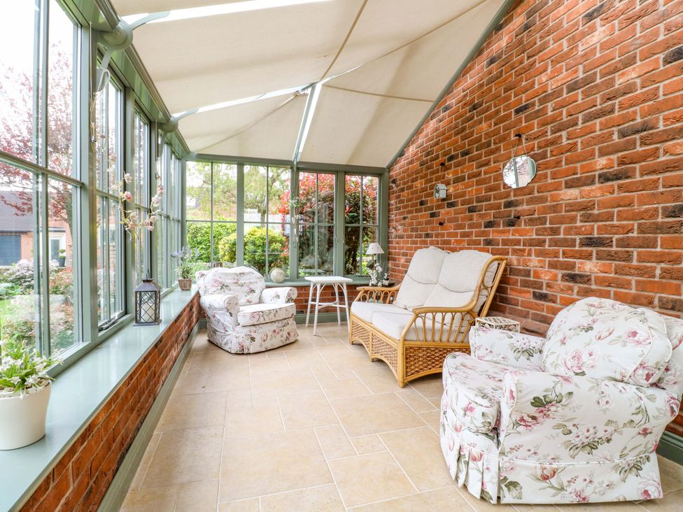 A conservatory with seating and plants at The Garden House in Alton