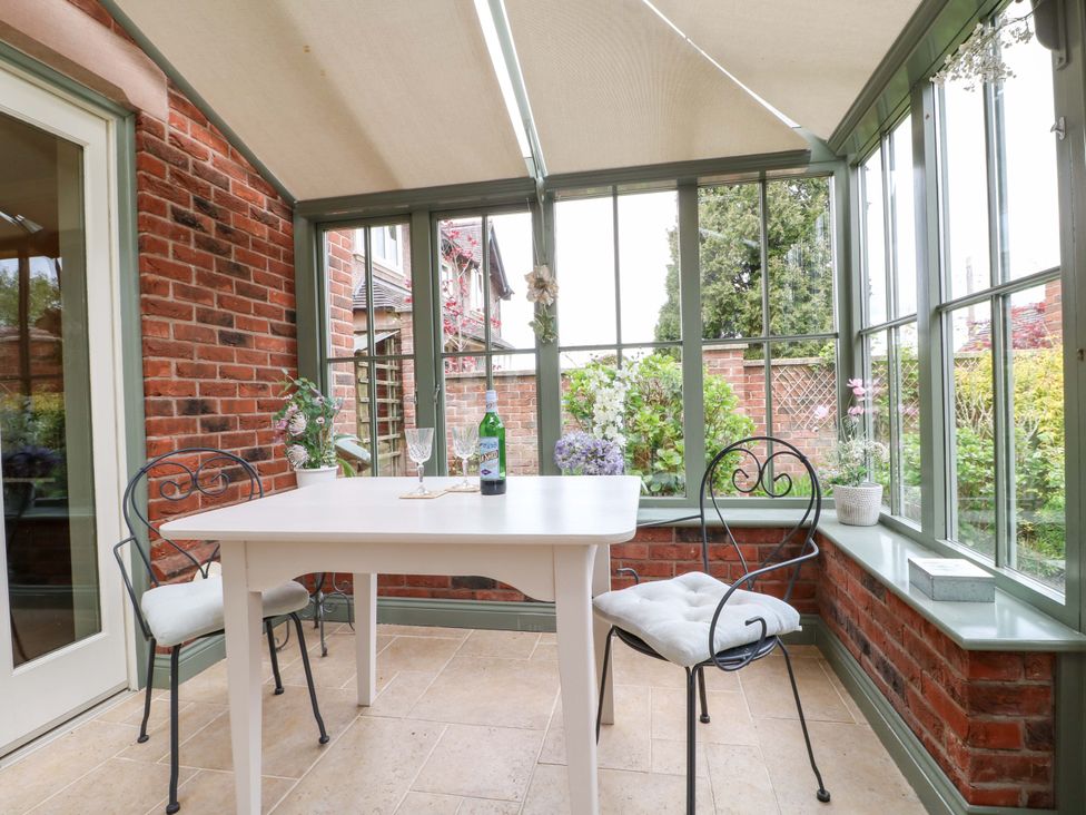A conservatory with a table and chairs at The Garden House in Alton