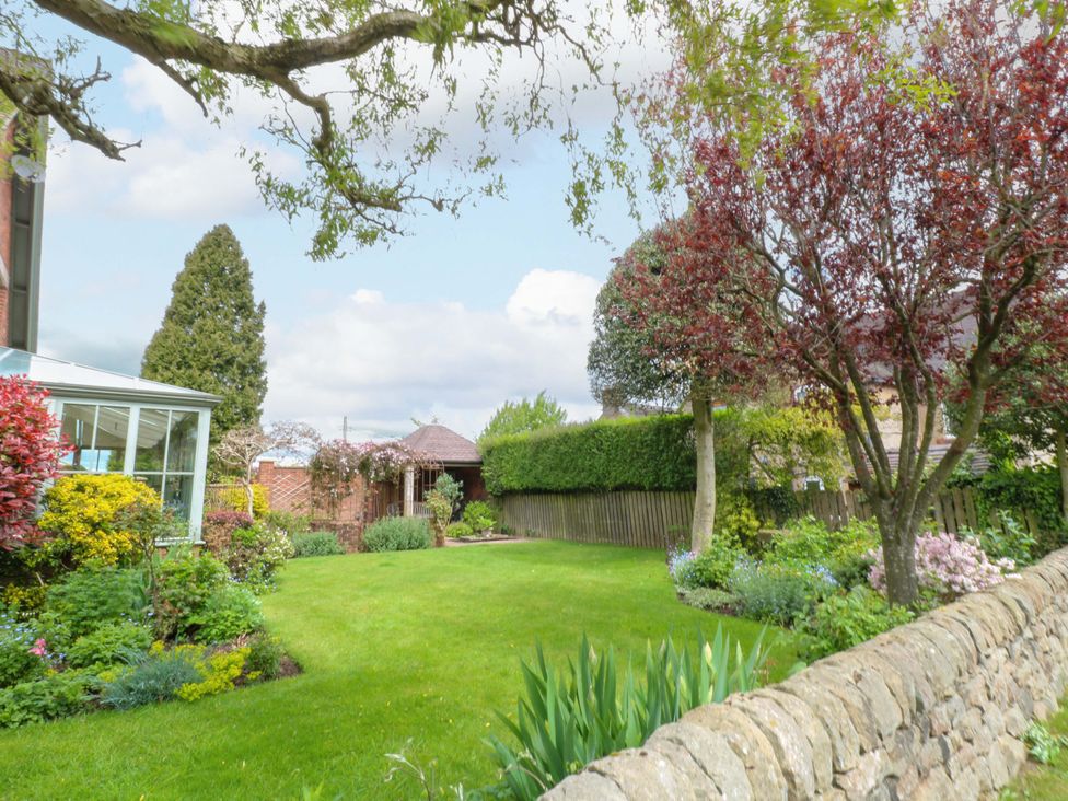 A garden with trees and a conservatory at The Garden House in Alton